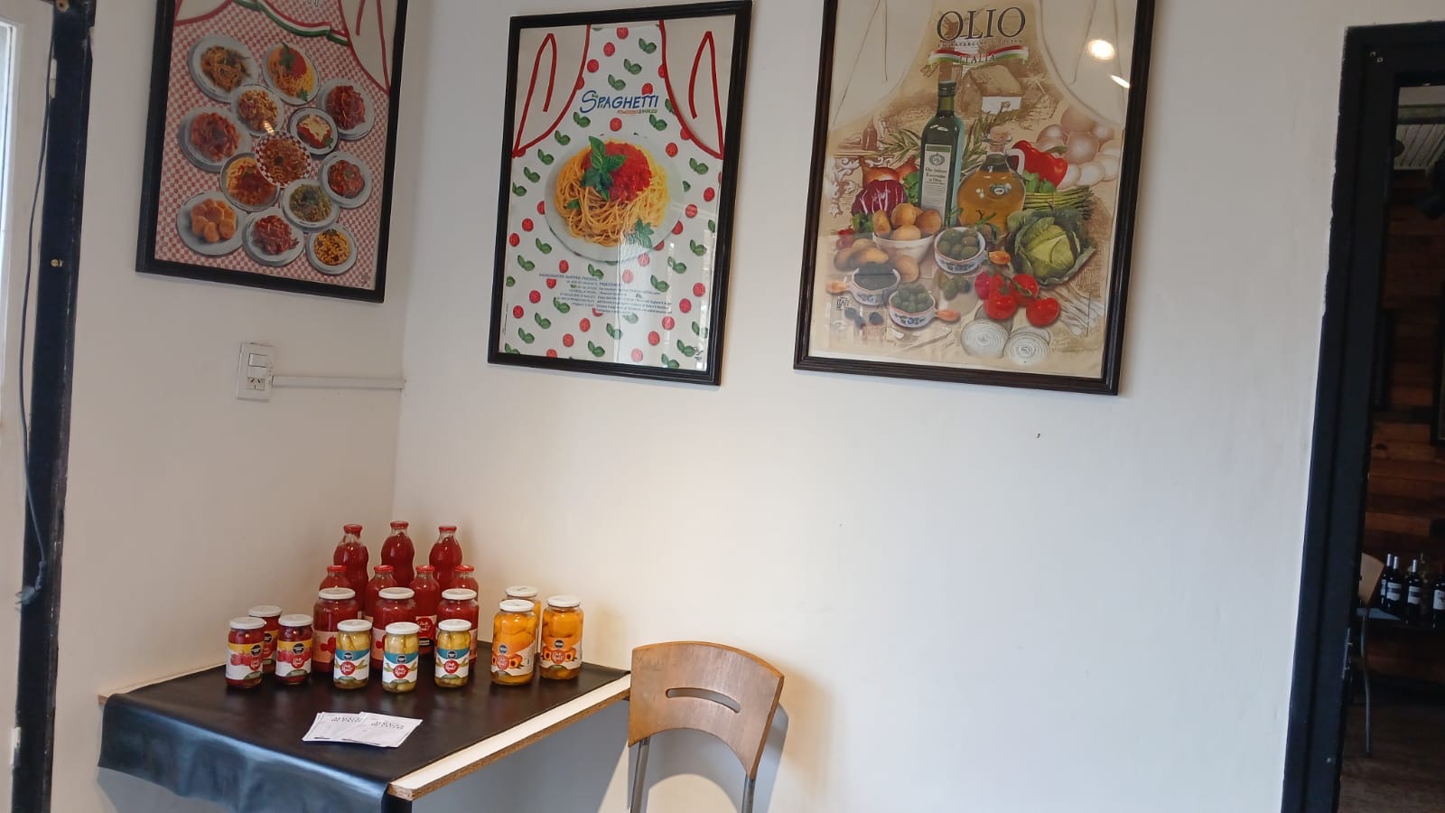Rincón del almacén con afiches italianos y conservas sobre la mesa