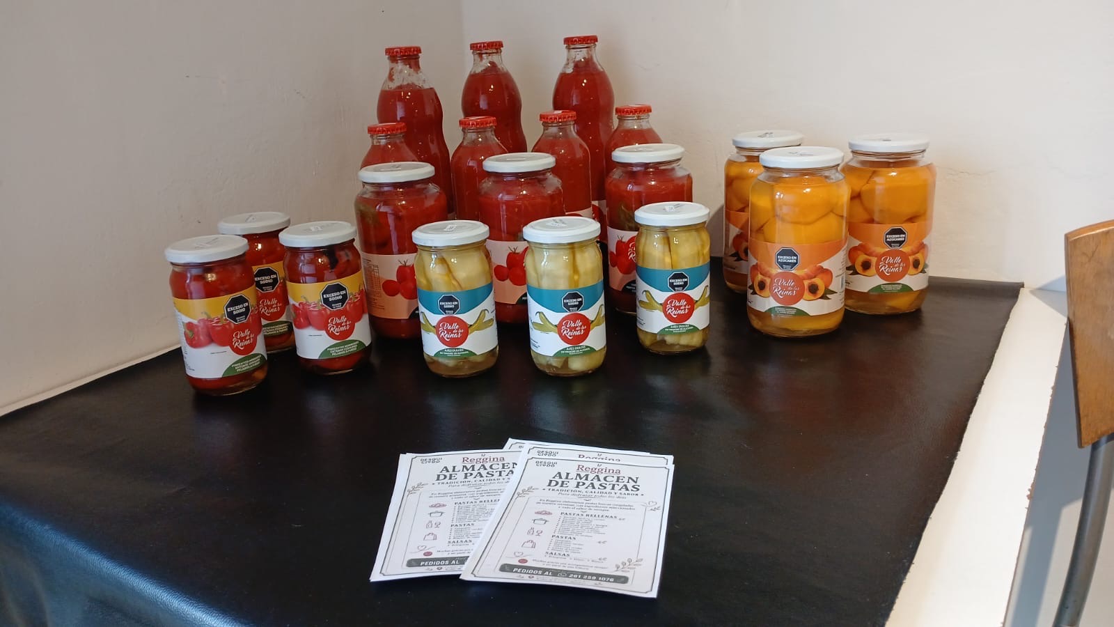 Salsas de tomate, duraznos y conservas junto a la carta de Reggina